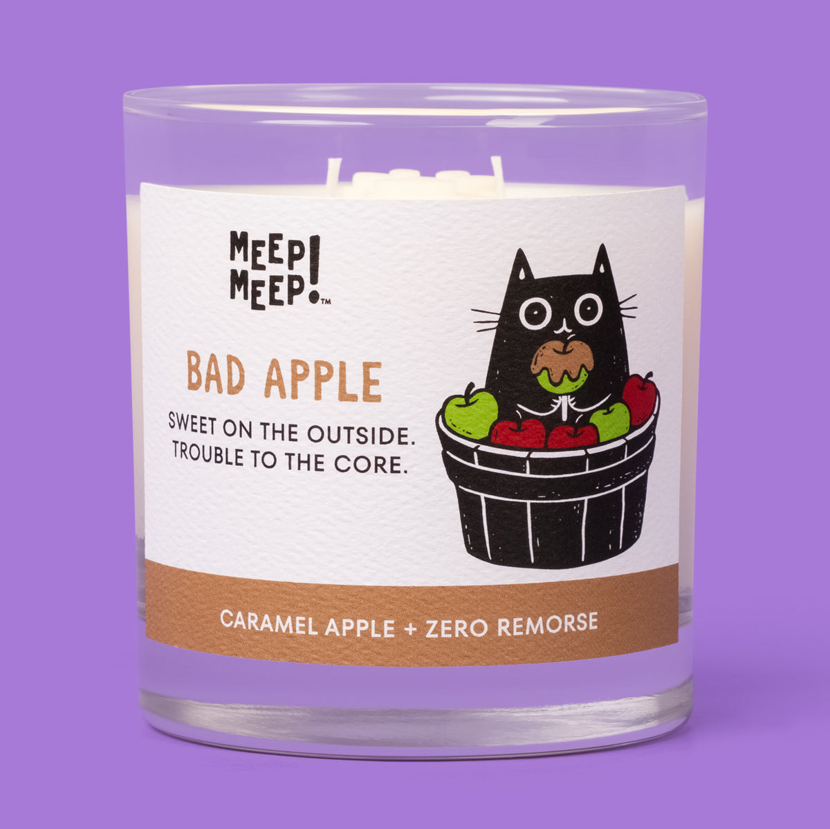 Meep Meep Bad Apple candle in a clear glass jar, with a label showing a black cat holding a caramel apple in an apple basket.