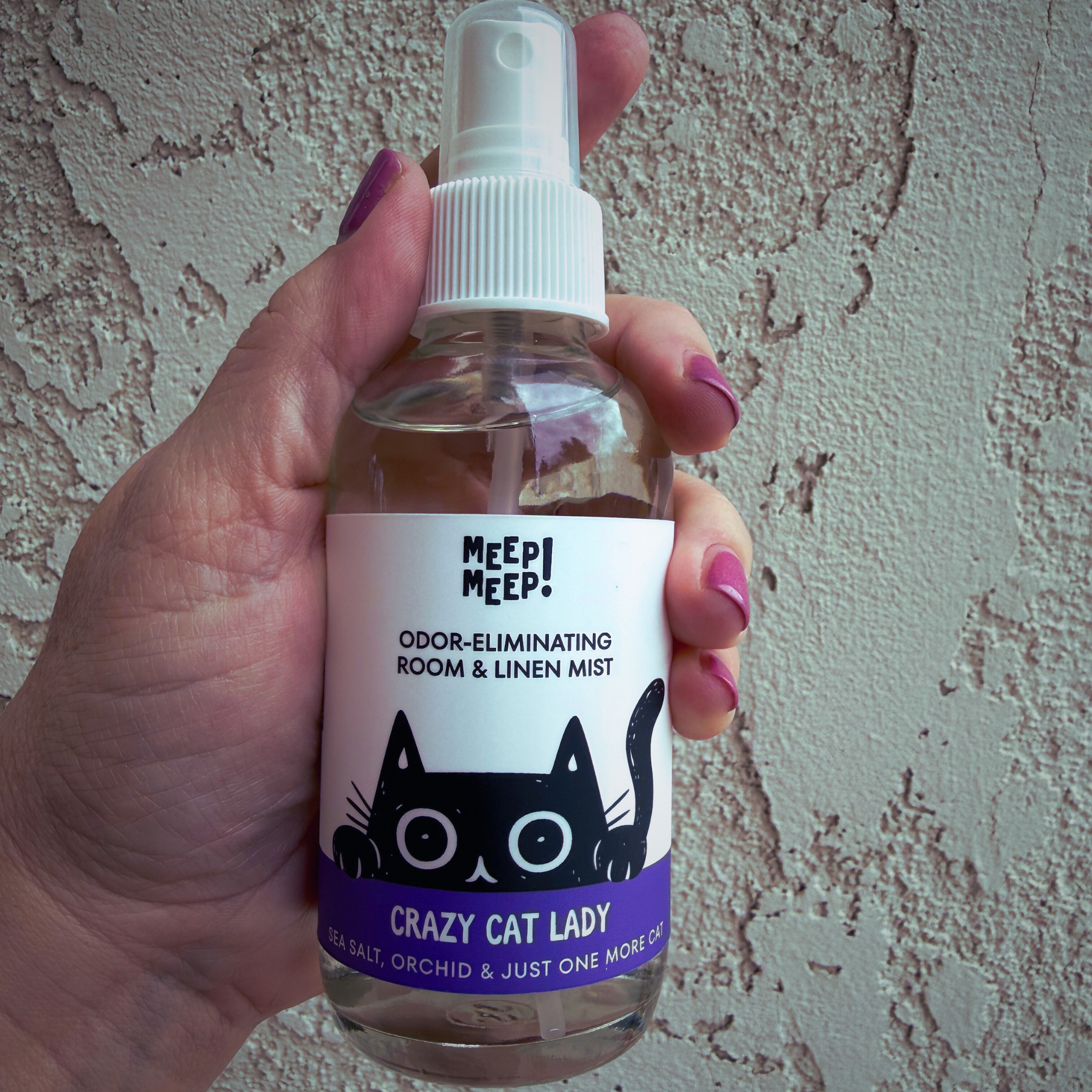 Image of glass bottle with illustration of black cat peeking out. Label on bottle reads: Meep Meep Odor-eliminating room & linen spray. "Crazy Cat Lady" , sea salt, orchid & just one more cat.