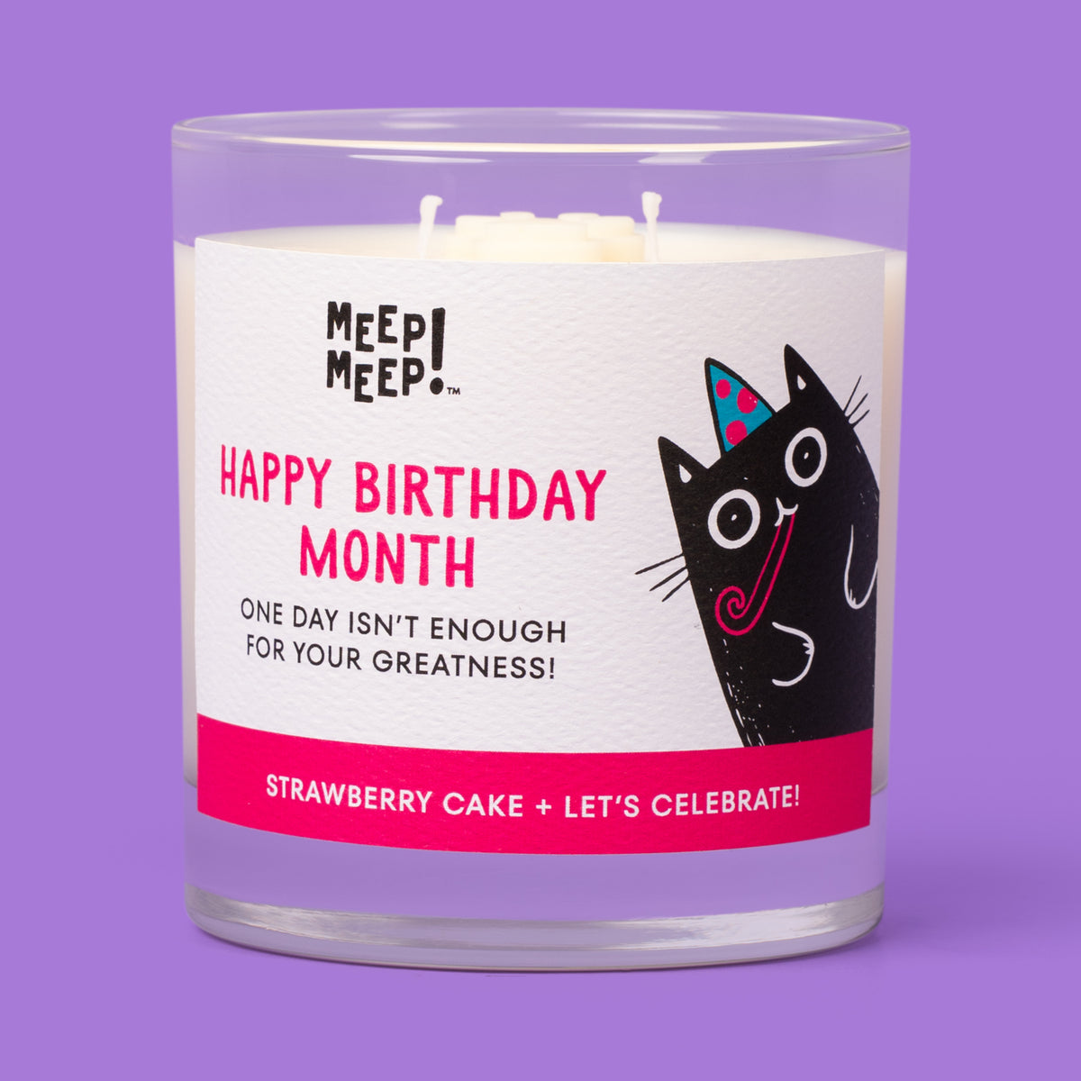 Meep Meep Happy Birthday Month candle in a clear glass jar with a label featuring a black cat wearing a party hat. 