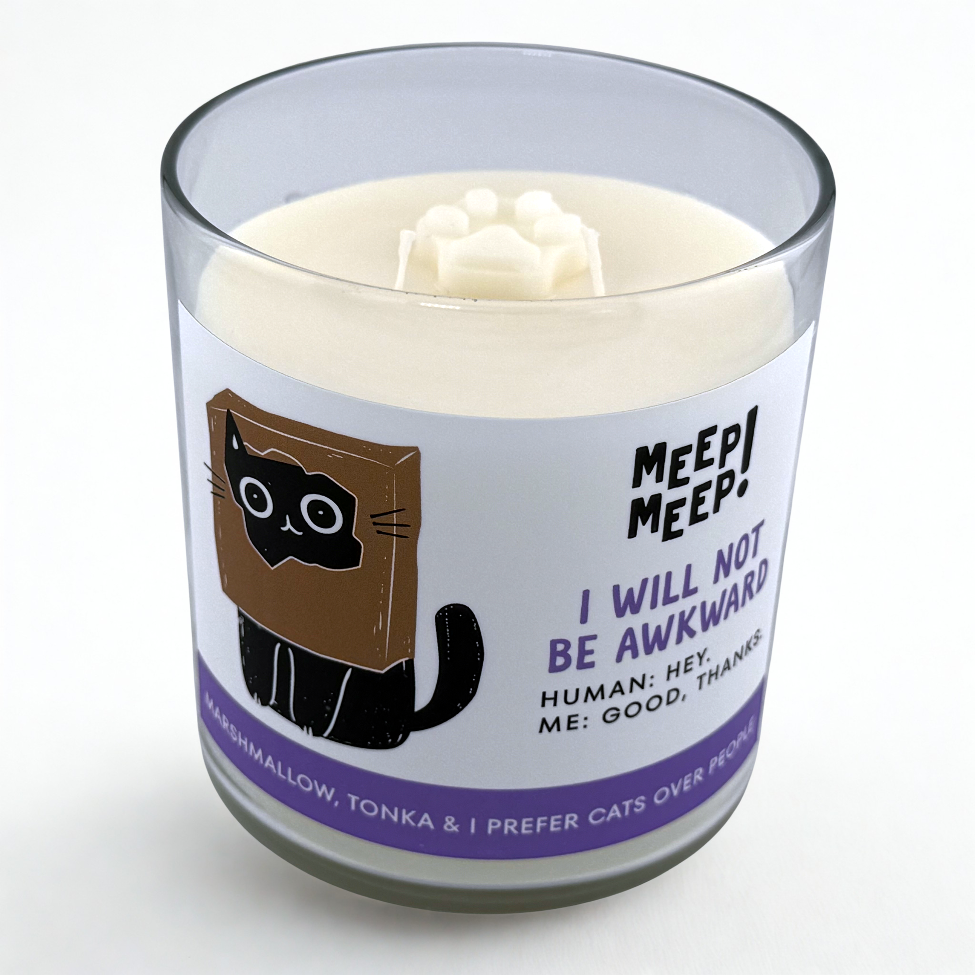 Photograph of Meep Meep candle with wax paw print embed on top. Label has an Illustration of a black cat with a brown paper bag over its head. Text on white background says "I Will Not
Be Awkward. Human: Hey.
Me: Good, thanks."
Bottom of candle label reads Marshmallow, tonka & I prefer cats over people