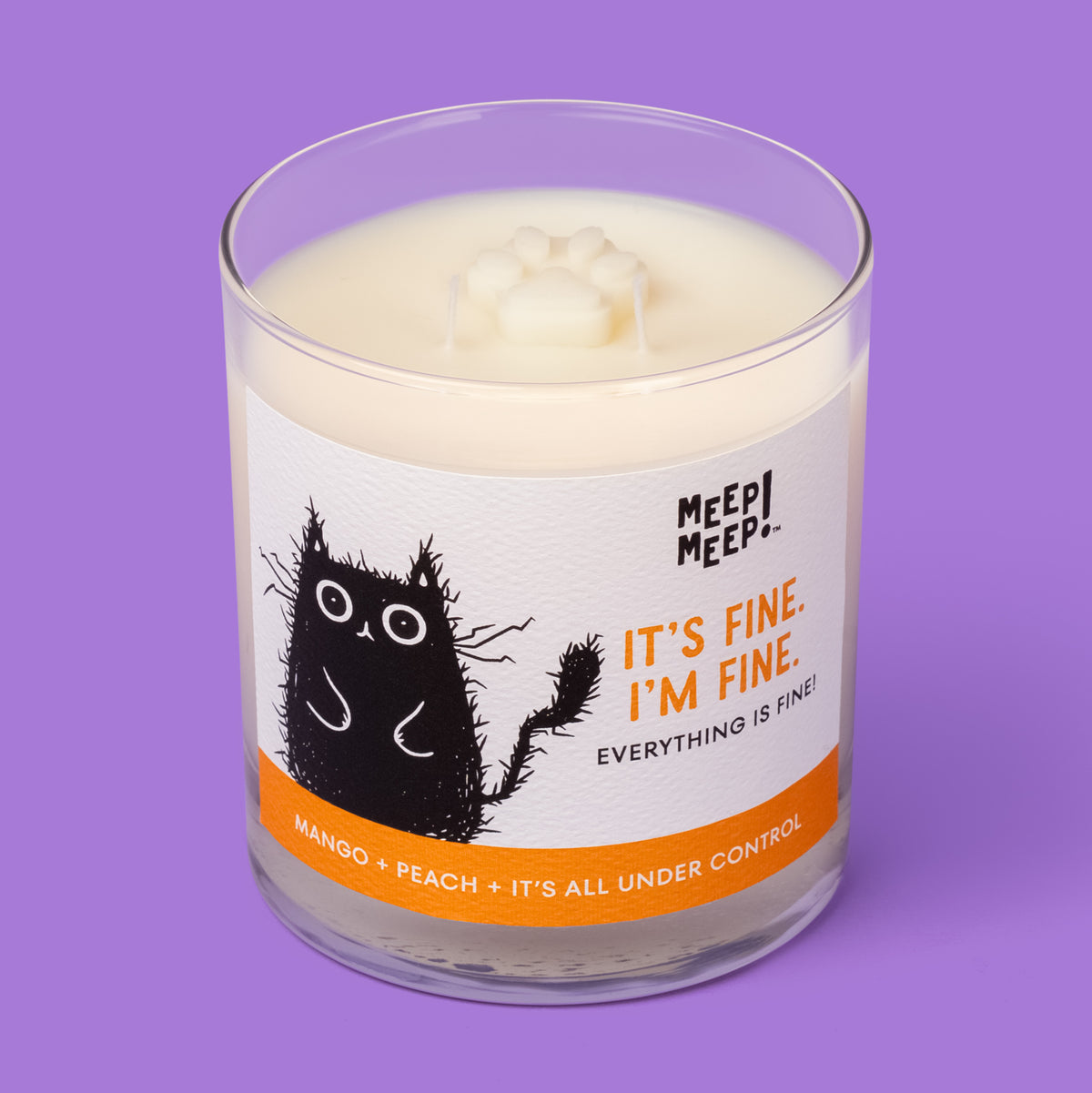 Meep Meep It’s Fine. I’m Fine. candle in a clear glass jar with an orange-accented label featuring a wide-eyed, frazzled black cat. Jar is angled so we can see the paw embed on top of candle.
