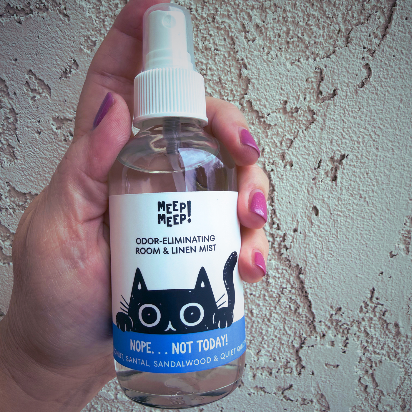 Image of glass bottle with illustration of black cat peeking out. Label on bottle reads: Meep Meep Odor-eliminating room & linen spray. "Nope...Not Today" , coconut, santal & quiet quitting.