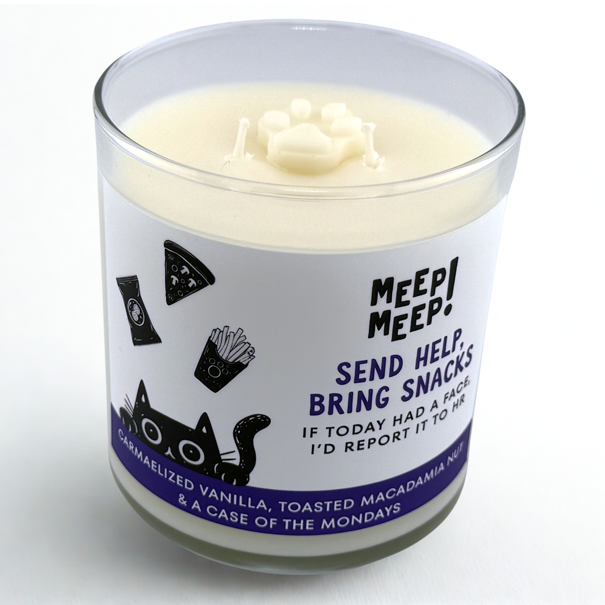 Photograph of Meep Meep candle with wax paw print embed on top. Label has an Illustration of a black cat peeking head up from floor, above cats head is a bag of peanuts, a slice of pizza and french fries. Text on white background says "Send Help, Bring Snacks. If Today had a face I'd report it to HR."
Bottom of candle label reads CARMAELIZED VANILLA, TOASTED MACADAMIA NUT& a case of the Mondays