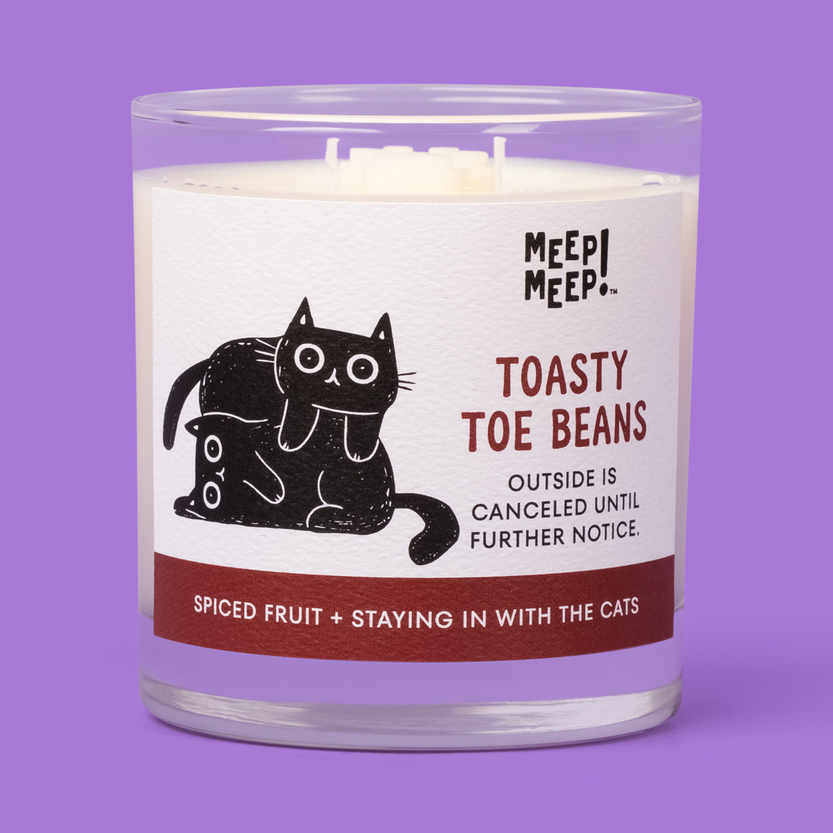 Meep Meep Toasty Toe Beans candle in a clear glass jar with a label showing two black cats snuggled together.