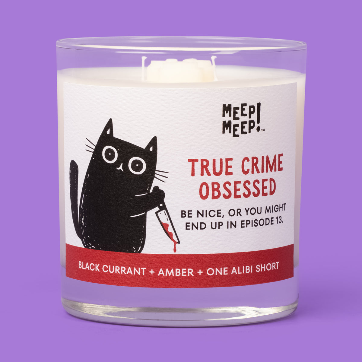 Meep Meep True Crime Obsessed candle in a clear glass jar with a label showing a black cat holding a bloodstained knife.